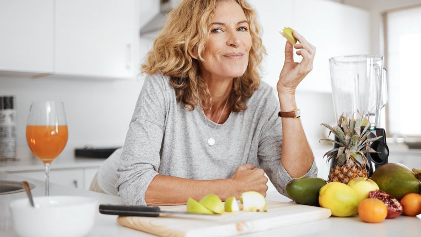 Frau genießt frisches Obst und Gemüse in einer hellen Küche